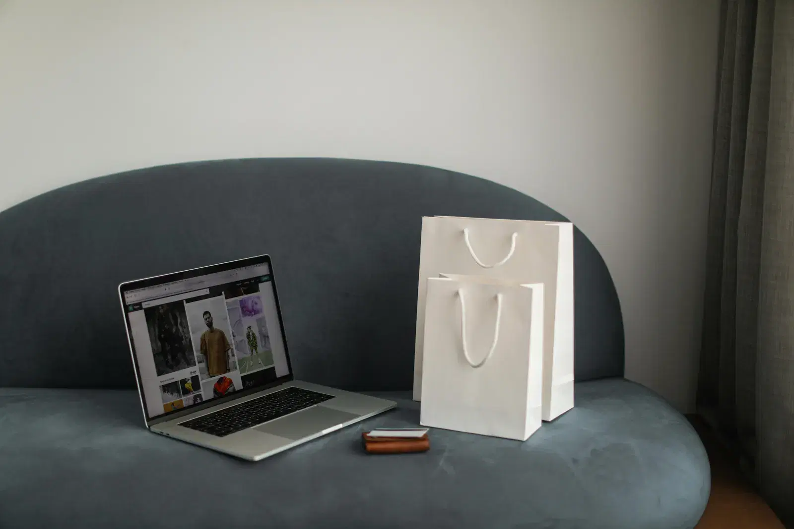 Online shopping setup with a laptop and shopping bags on a stylish couch.